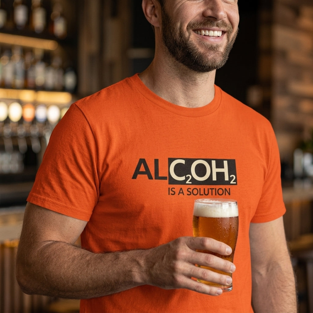 Smiling man wearing an orange Alcohol Is A Solution T-shirt with chemistry-inspired lettering while holding a glass of beer.