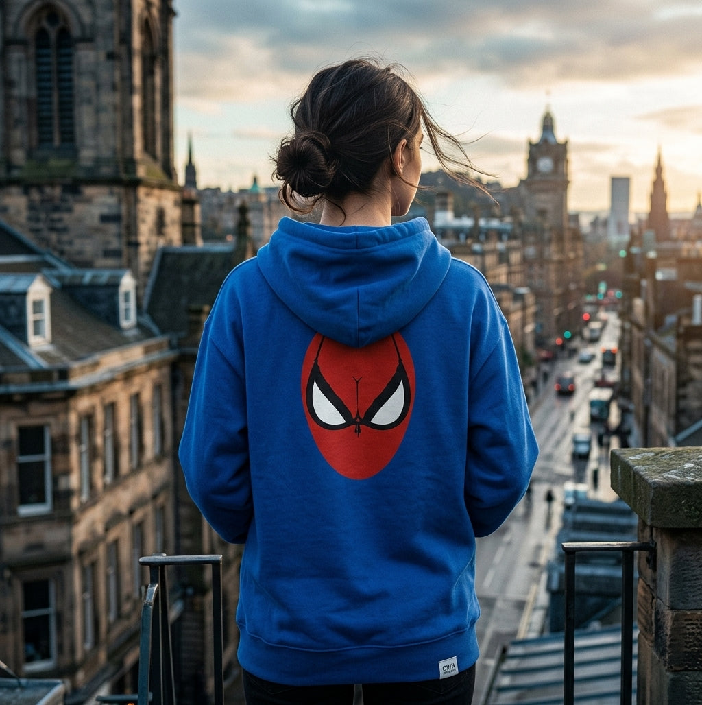 Rear view of a woman wearing a blue Spider Brassière Hoodie with a red superhero-inspired graphic overlooking a city street.