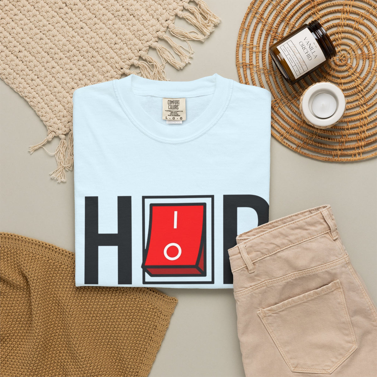Light blue Hip Hop Switch T-Shirt folded beside beige trousers and a candle.